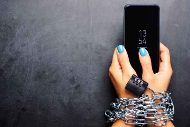 kvinnas händer är fastkedjade med kodlås vid mobiltelefon