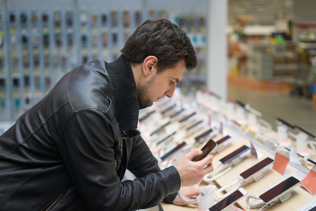 En man tittar på smartphones i butik