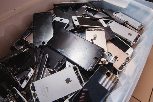 Flera trasiga mobiltelefoner från Apple i en stor plastlåda