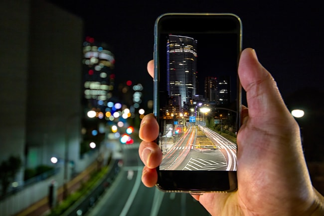 någon tar foto på stadsvy på natten med en mobiltelefon