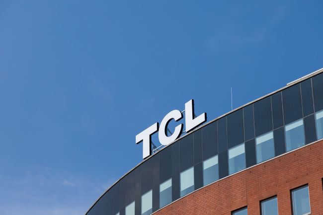 Bokstäverna tcl på hustak mot blå himmel.