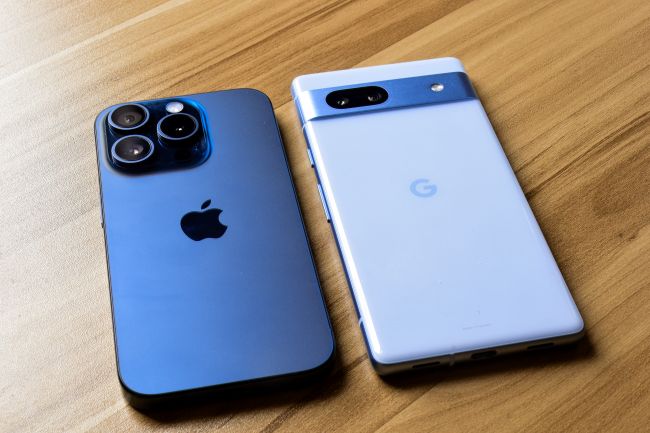 En apple- respektive googlepixel-mobil ligger bredvid varandra på träbord.